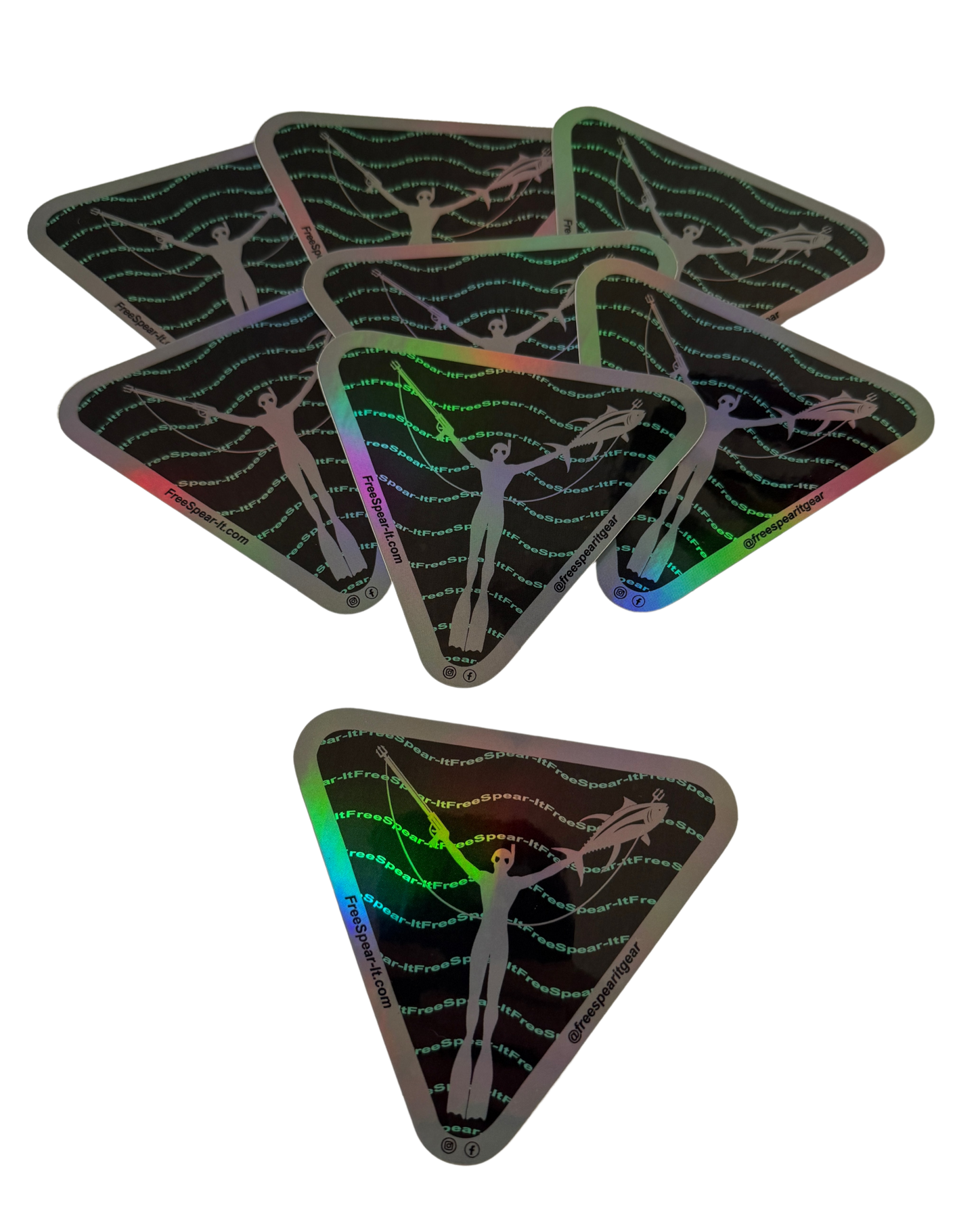 A stack of Free Spear-It Iconic Waves 4-Inch Holographic Stickers featuring a sleek silhouette of a freedive spearfisher holding a speargun and fish. The bold design includes wave-like Free Spear-It text lines in teal against a black background with a metallic grey border. The website FreeSpear-It.com and social media handle @freespearitgear are printed in the border of the stickers